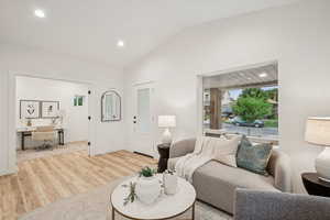 Living area with vaulted ceiling, recessed lighting, wood finished floors, and a desk