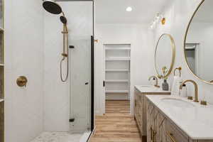Bathroom with light wood-style flooring, a shower stall, vanity, recessed lighting, and a walk in closet