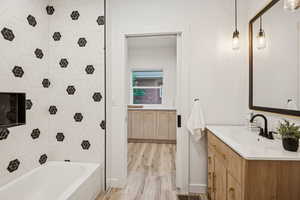 Bathroom with vanity, washtub / shower combination, and light wood-style floors