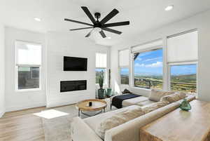 Living area featuring wood finished floors, recessed lighting, a large fireplace, and a ceiling fan