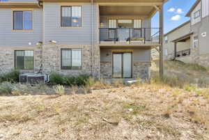 Rear view of house featuring stone siding and a balcony