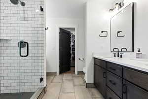 Bathroom with a shower stall, double vanity, and a spacious closet