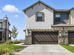 Craftsman-style house featuring a garage, board and batten siding, stone siding, and driveway