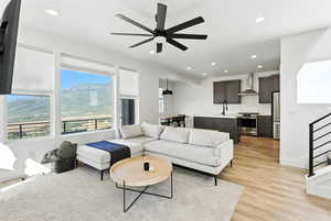Living area with recessed lighting, a ceiling fan, light wood-style floors, and stairway