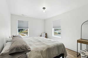 Bedroom with multiple windows and light wood-style floors
