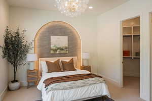 Carpeted bedroom with a spacious closet, a chandelier, and recessed lighting