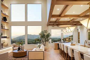 Living area with a mountain view, light wood-style flooring, recessed lighting, and beamed ceiling