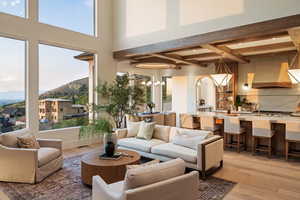 Living area featuring light wood-style flooring, a mountain view, beamed ceiling, and a chandelier