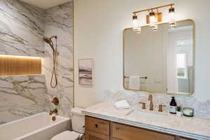 Full bath with a combined bath / shower with marble appearance and vanity