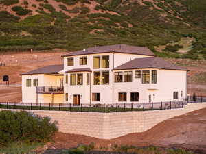 Rear view of property featuring stucco siding, a balcony, a patio area, and roof with shingles