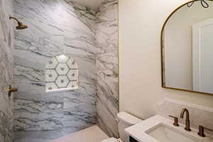Full bath featuring a marble finish shower and vanity