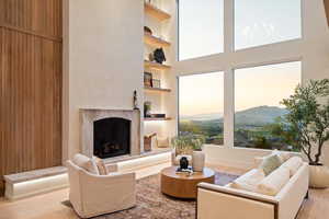 Living area featuring built in shelves, light wood-style floors, a mountain view, a fireplace, and a high ceiling