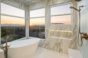 Full bath featuring a freestanding bath and a marble finish shower