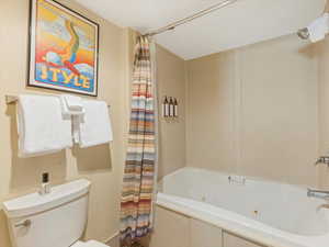 Full bathroom #1 with a combined bath / shower with jetted tub and toilet
