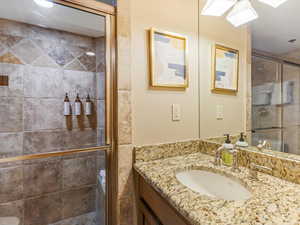 Bathroom #2 featuring vanity, a shower stall, and a textured wall