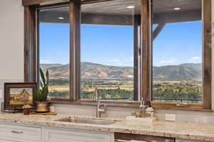 Kitchen view of light stone countertops, tasteful backsplash, and white cabinets