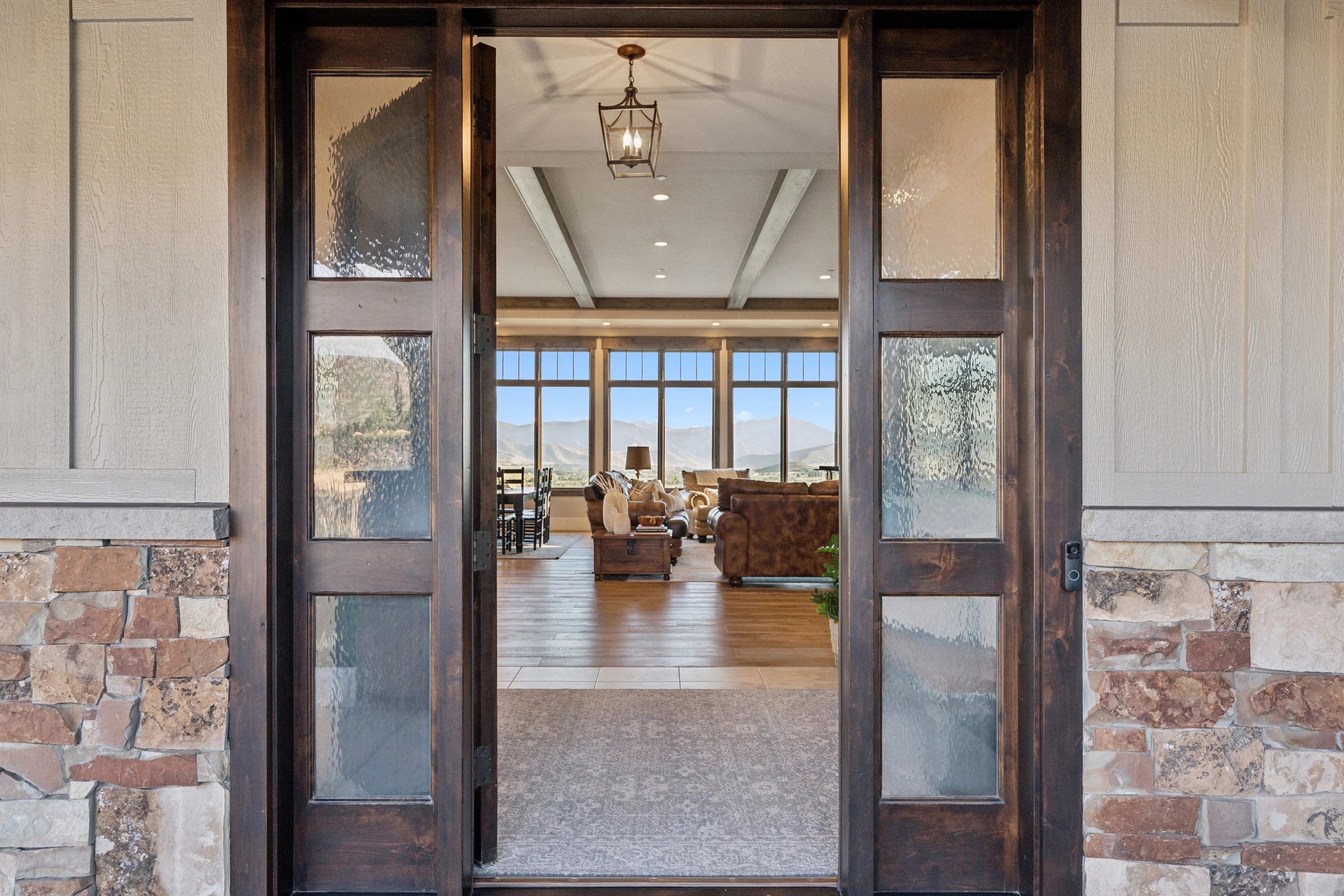 Doorway to property featuring a mountain view, stone siding, and a patio