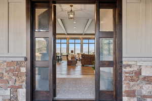 Doorway to property featuring a mountain view, stone siding, and a patio