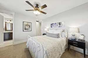 Bedroom featuring light colored carpet, ceiling fan, and ensuite bath