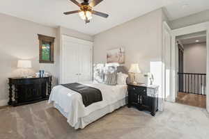 Bedroom with light carpet, a closet, and a ceiling fan