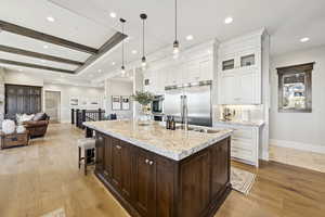 Kitchen with glass insert cabinets, open floor plan, a breakfast bar area, white cabinets, and a center island with sink