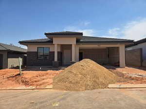 Prairie-style house with a garage, stucco siding, and a tiled roof