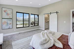 Carpeted bedroom with a barn door, a mountain view, recessed lighting, and ensuite bath