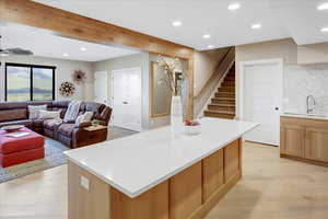 Kitchen with recessed lighting, backsplash, beam ceiling, light wood-style flooring, and light brown cabinets