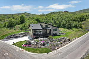 View of front of home featuring an attached garage, concrete driveway, a deck with mountain view, and a forest view