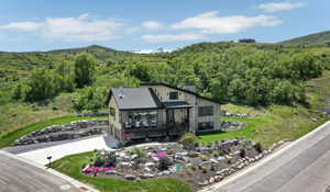 View of front of home featuring driveway, a wooded view, a deck with mountain view, a garage, and a chimney