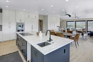 Kitchen with recessed lighting, white cabinets, ceiling fan, and light stone counters