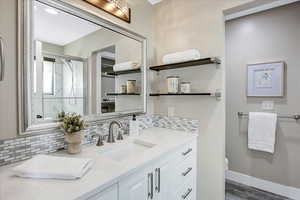 Bathroom with vanity, decorative backsplash, a shower stall, dark wood-type flooring, and a closet
