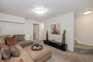 Carpeted living room featuring stairs and a textured ceiling