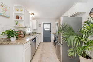 Kitchen with white cabinets, stainless steel appliances, and light stone countertops
