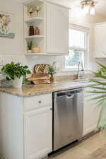 Kitchen with decorative backsplash, dishwasher, and white cabinets