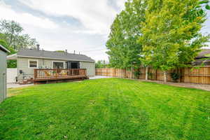 Fenced backyard featuring a wooden deck and a patio area
