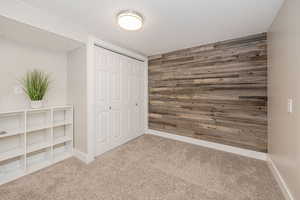 Unfurnished bedroom featuring wooden walls, a closet, and carpet flooring