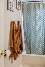 Full bathroom with shower / tub combo with curtain and baseboards