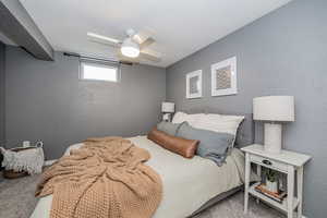 Carpeted bedroom featuring a textured wall, a ceiling fan, and a textured ceiling