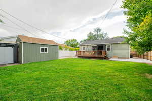 Fenced backyard with a deck, a patio area, and a storage unit