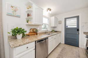 Kitchen featuring tasteful backsplash, appliances with stainless steel finishes, white cabinetry, and light stone countertops