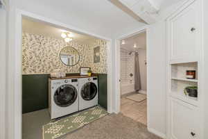 Laundry room featuring washing machine and dryer, electric panel, and light colored carpet