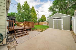 Fenced backyard featuring a storage shed, a patio, and a deck