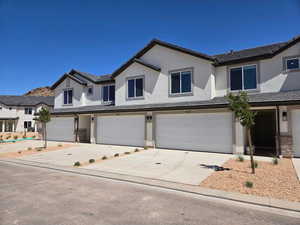 View of front of home with concrete driveway, stucco siding, an attached garage, and a tile roof