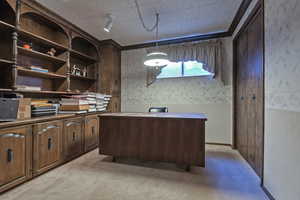 Office space with wallpapered walls, light carpet, and a wainscoted wall