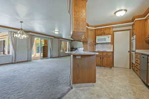 Kitchen featuring ornamental molding, brown cabinets, light countertops, light colored carpet, and a peninsula