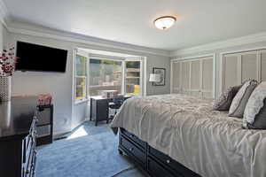 Bedroom featuring two closets, ornamental molding, and dark carpet