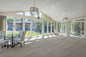 Sunroom featuring a chandelier, beamed ceiling, high vaulted ceiling, outdoor dining area, and carpet floors