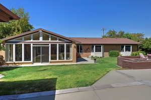 Rear view of house with brick siding, a sunroom, a yard, and a patio area
