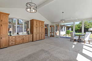 Living area featuring a chandelier, beamed ceiling, light carpet, healthy amount of natural light, and high vaulted ceiling